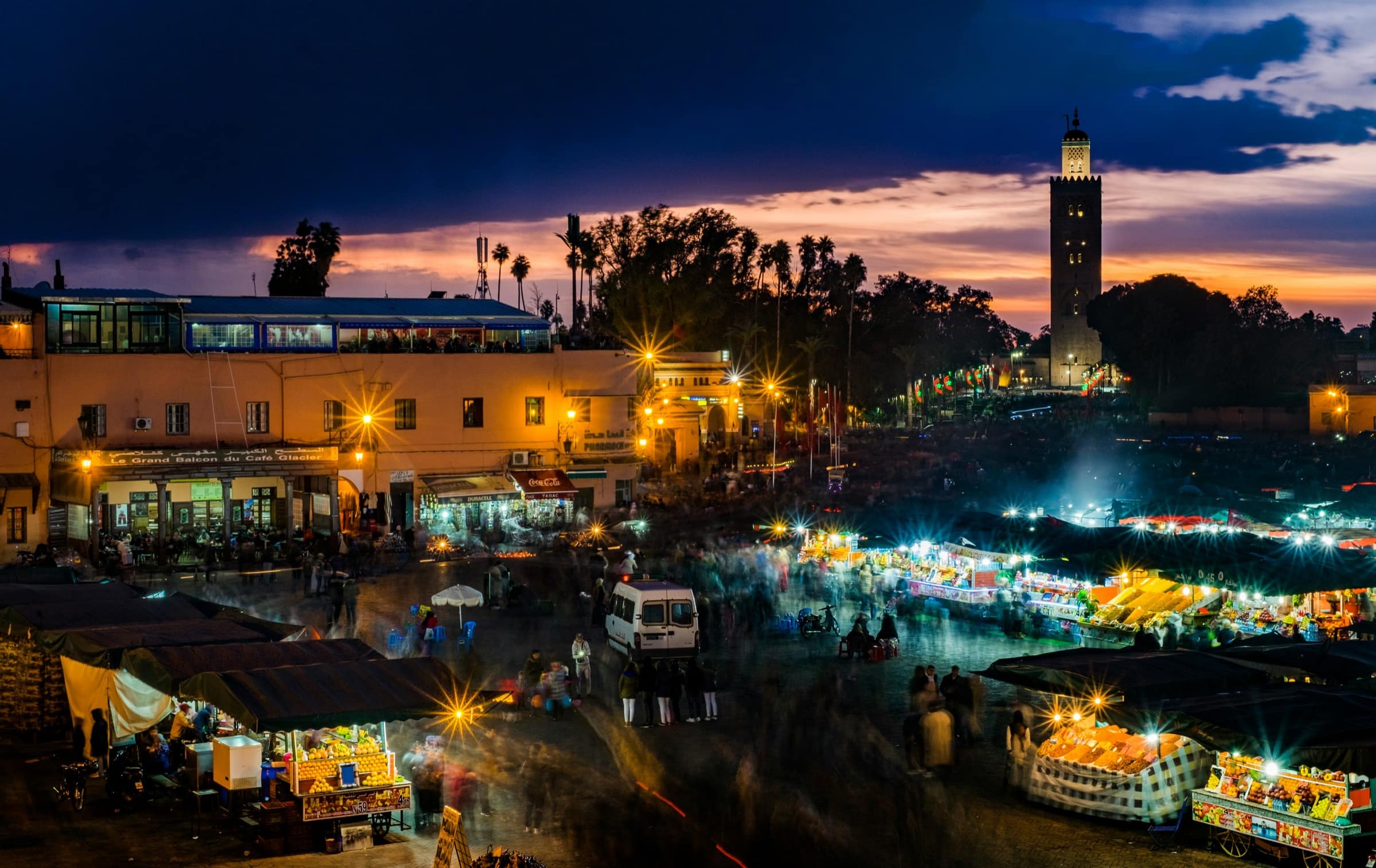 Vue de Jemaa el-Fna la nuit depuis une terrasse de café, lumières et brasseros