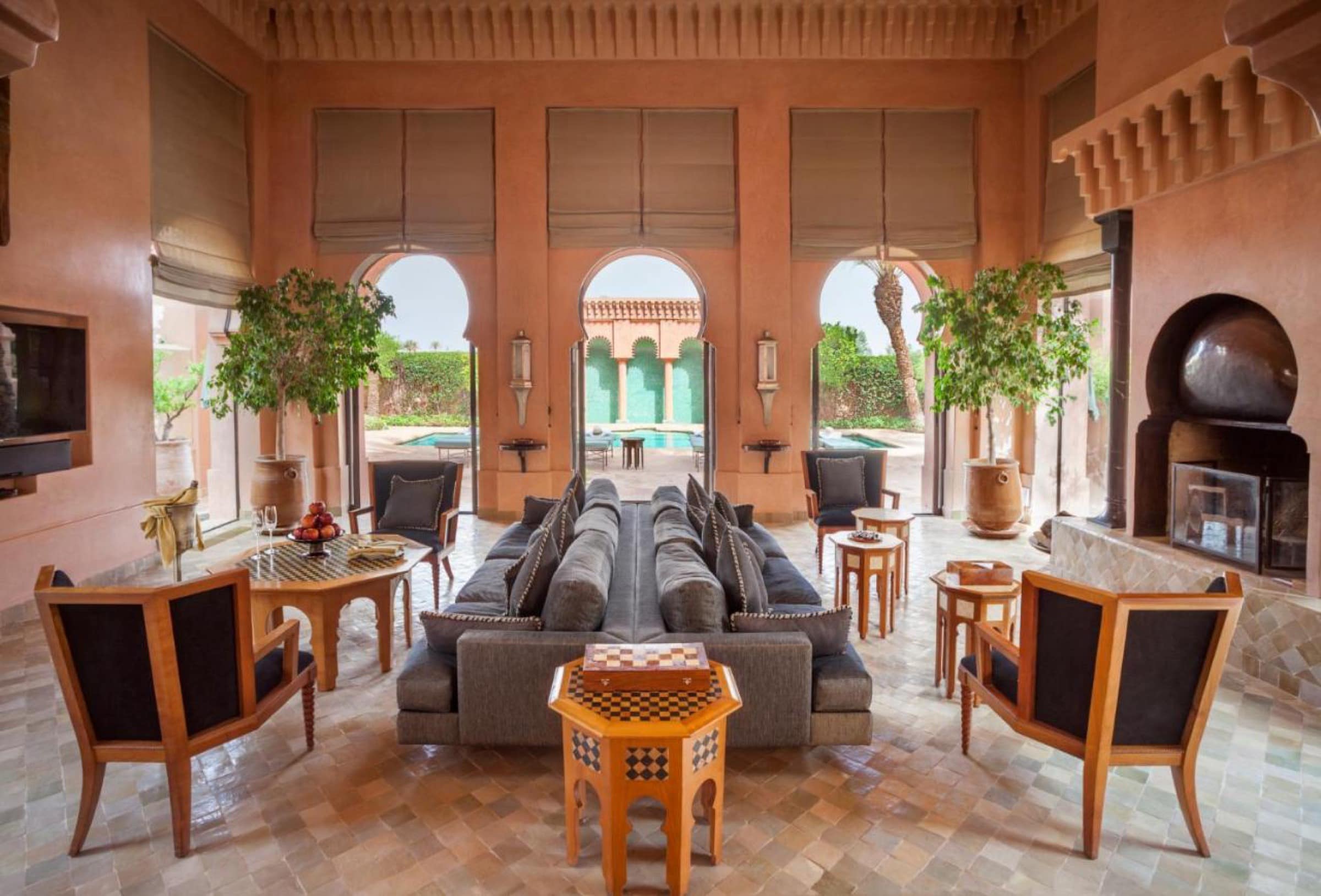 Le salon d'un pavillon, arches ouvertes sur une piscine privée