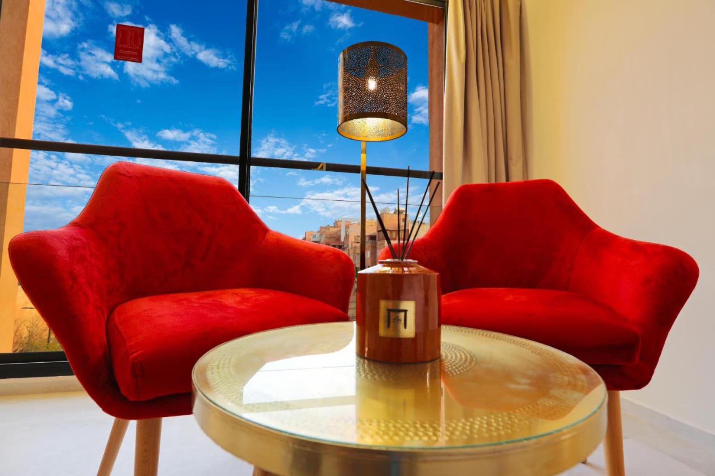 Un coin salon aux fauteuils rouges, face aux toits de la ville