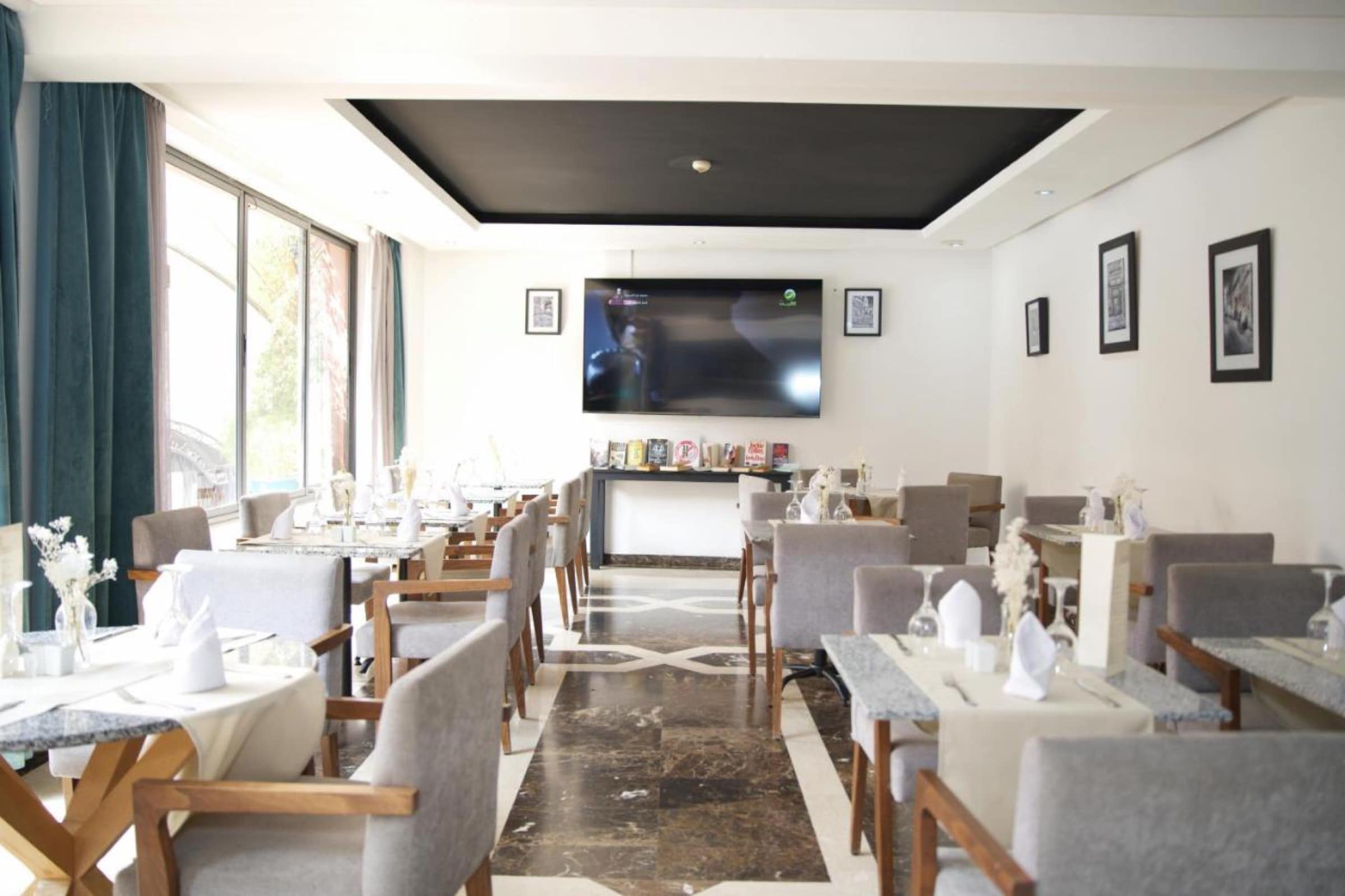 La salle de restaurant, tables dressées et grandes baies