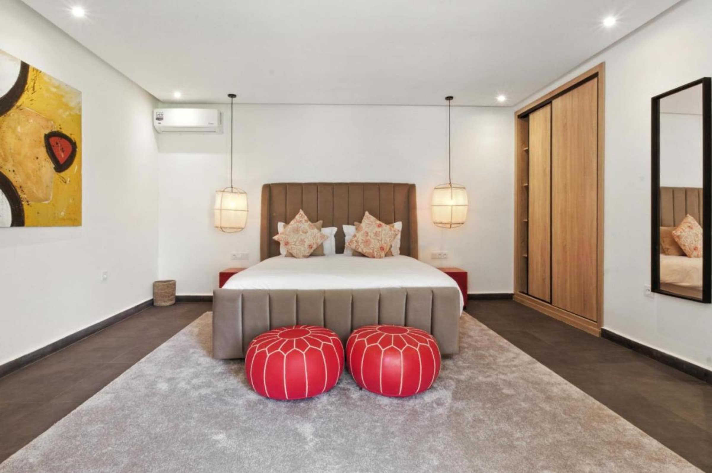 Une chambre épurée, poufs rouges et tête de lit capitonnée