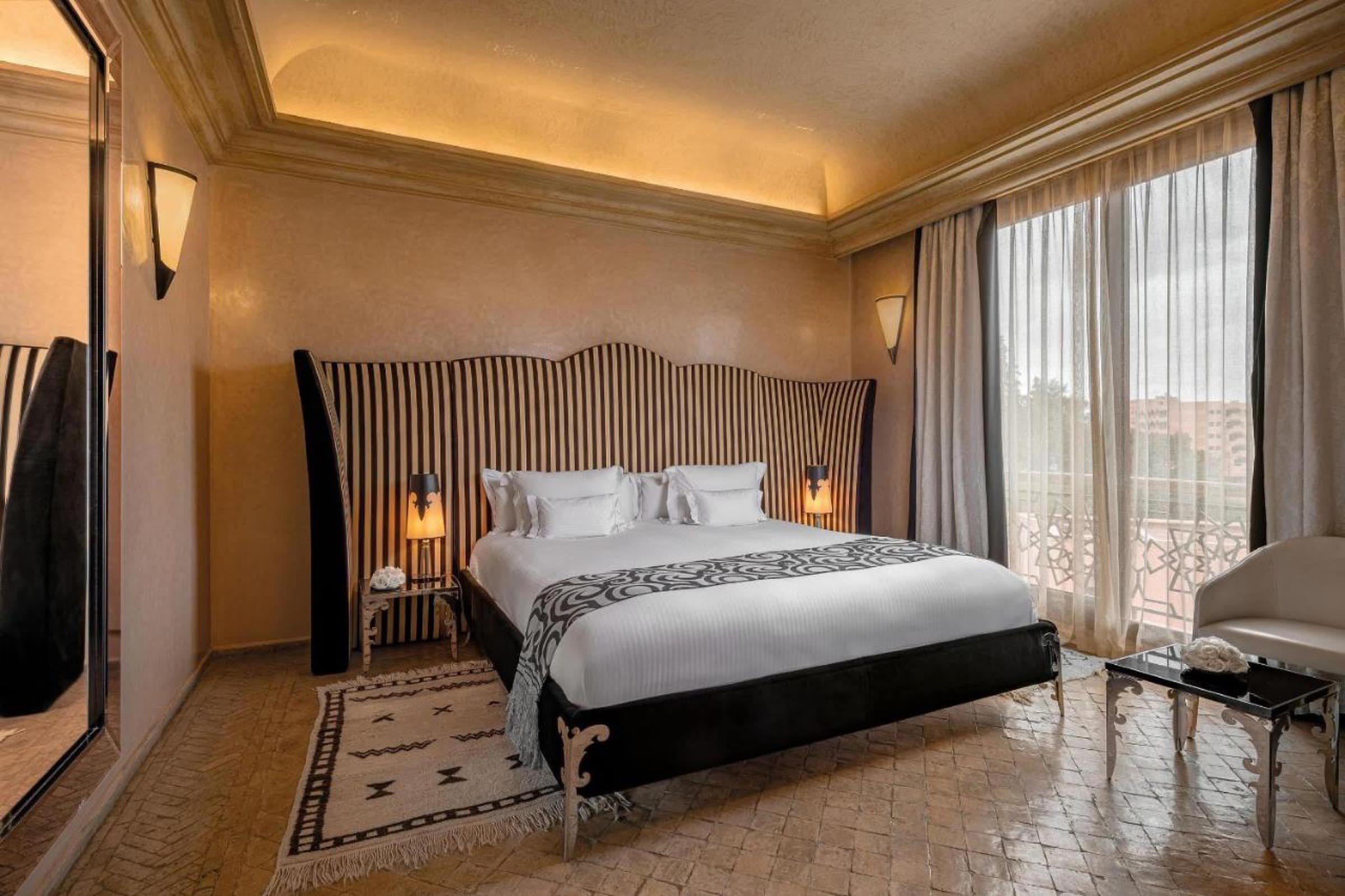 Une chambre à tête de lit rayée, baie sur la palmeraie
