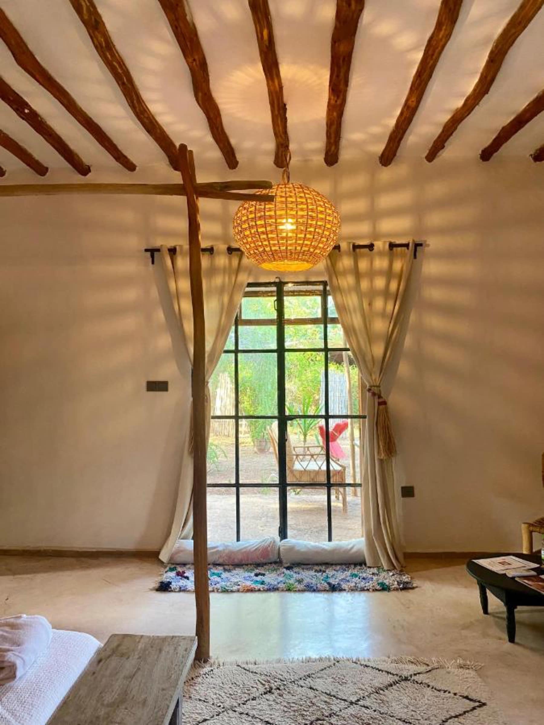 Une chambre sous plafond de troncs, ouverte sur le jardin