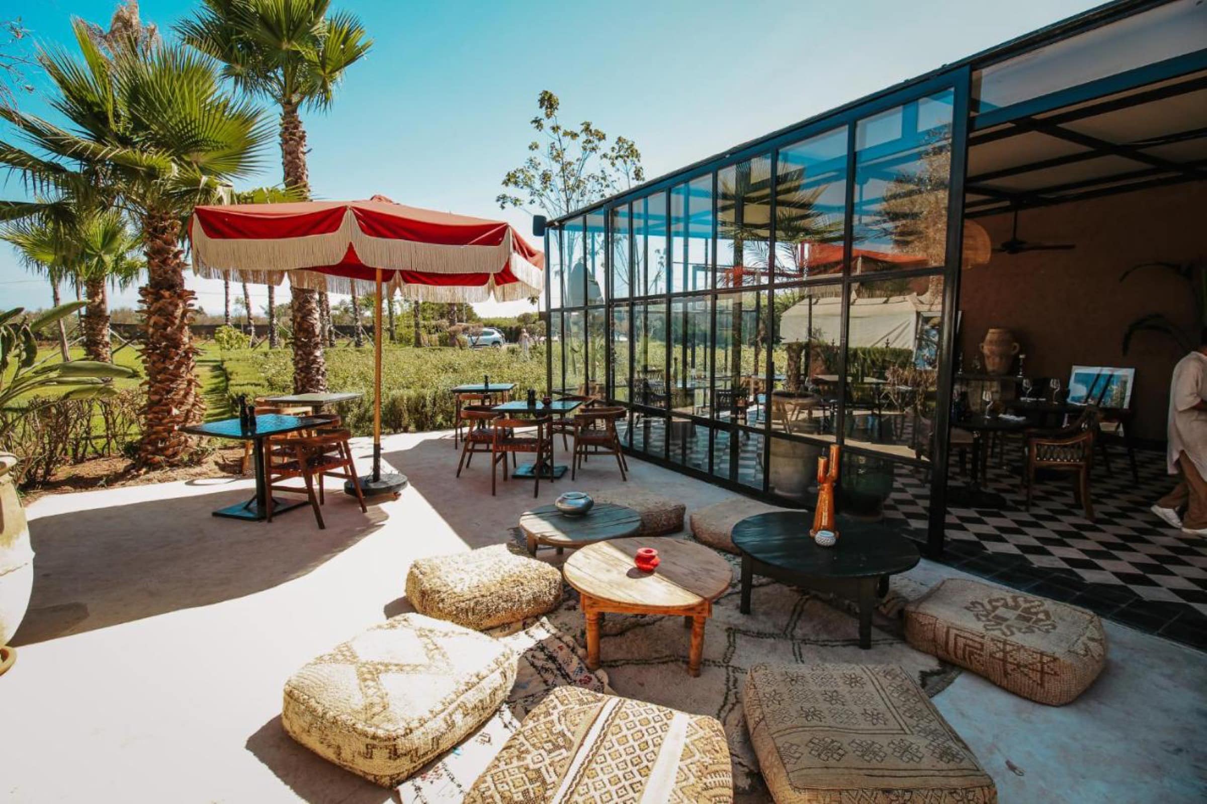 La terrasse basse, poufs et tapis, ouverte sur la campagne