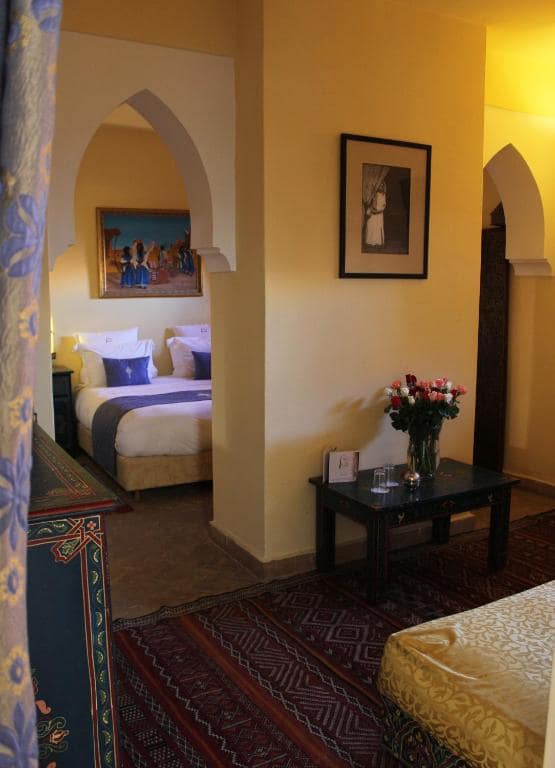 Une chambre aux murs ocre, ouverte sur un coin salon
