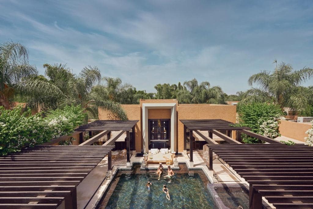 Une villa et sa piscine, vues du ciel, parmi les palmiers