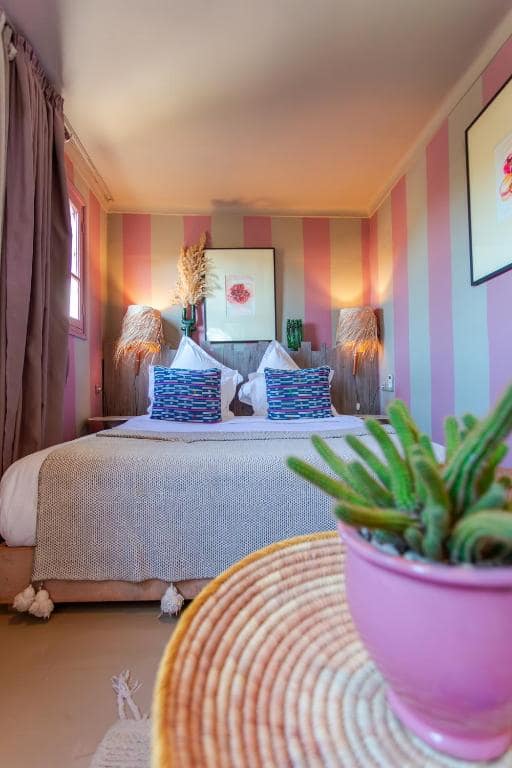 Une chambre, murs rayés et tête de lit en bois brut