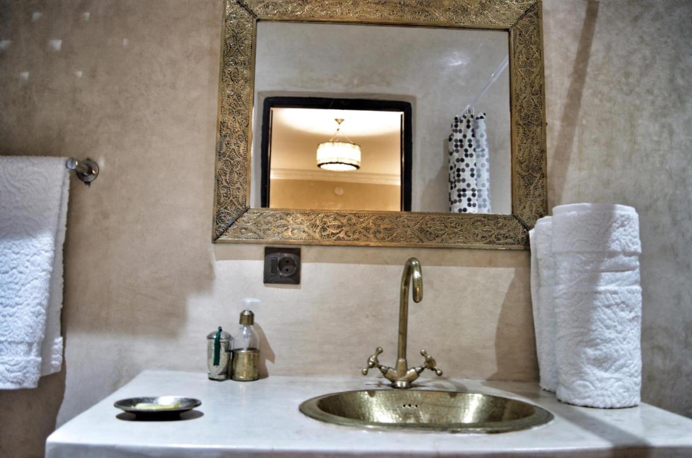 Une salle de bains, vasque en laiton martelé et miroir ciselé