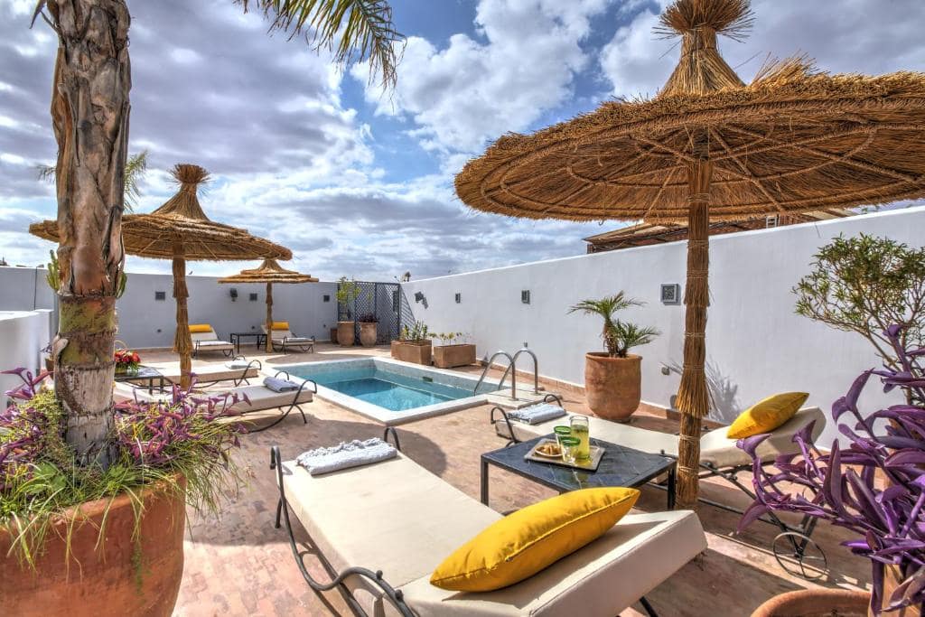 La terrasse de jour, parasols de paille, transats et bassin