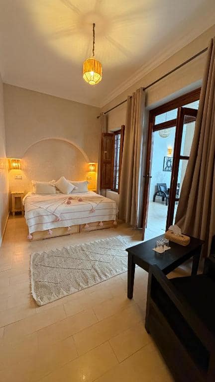 Une chambre claire, lit à tête arrondie et porte sur le patio