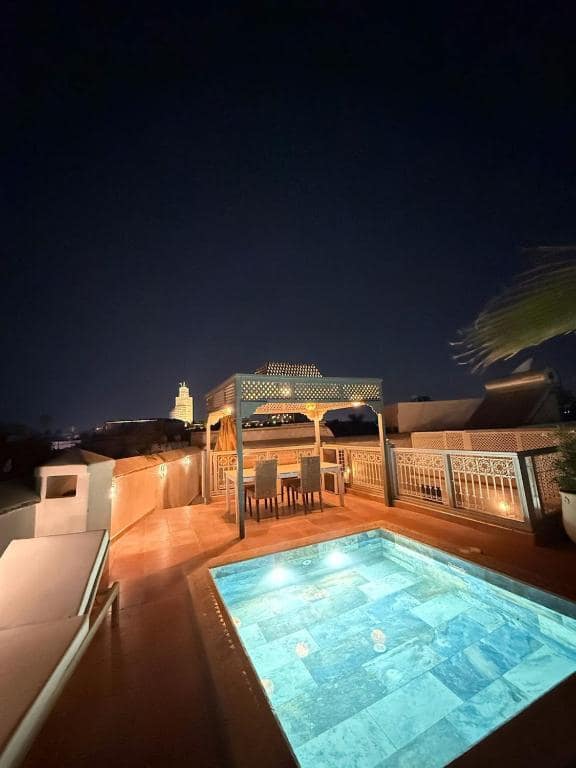 Le bassin du toit éclairé le soir, pergola et minaret au loin