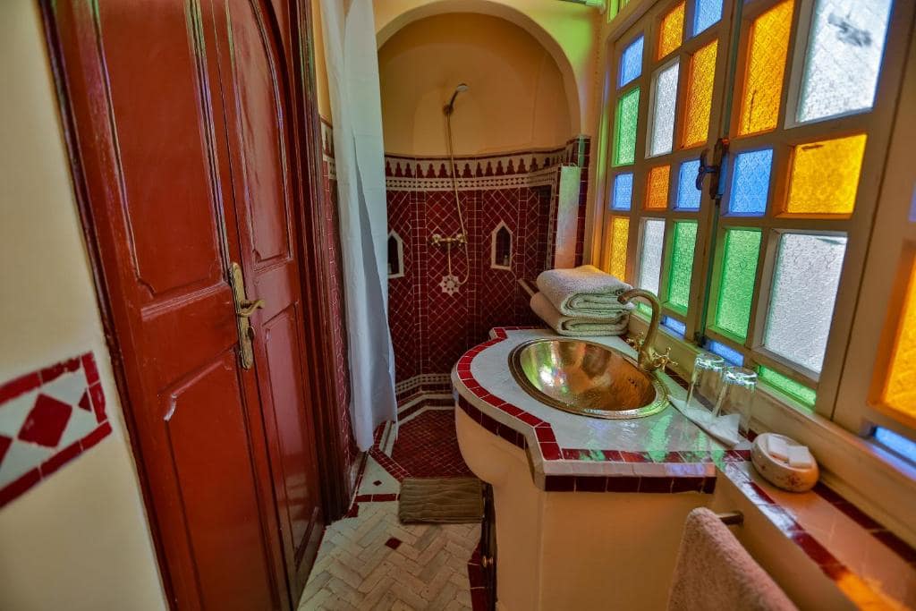 Une salle d'eau en zellige, vasque de cuivre et vitraux