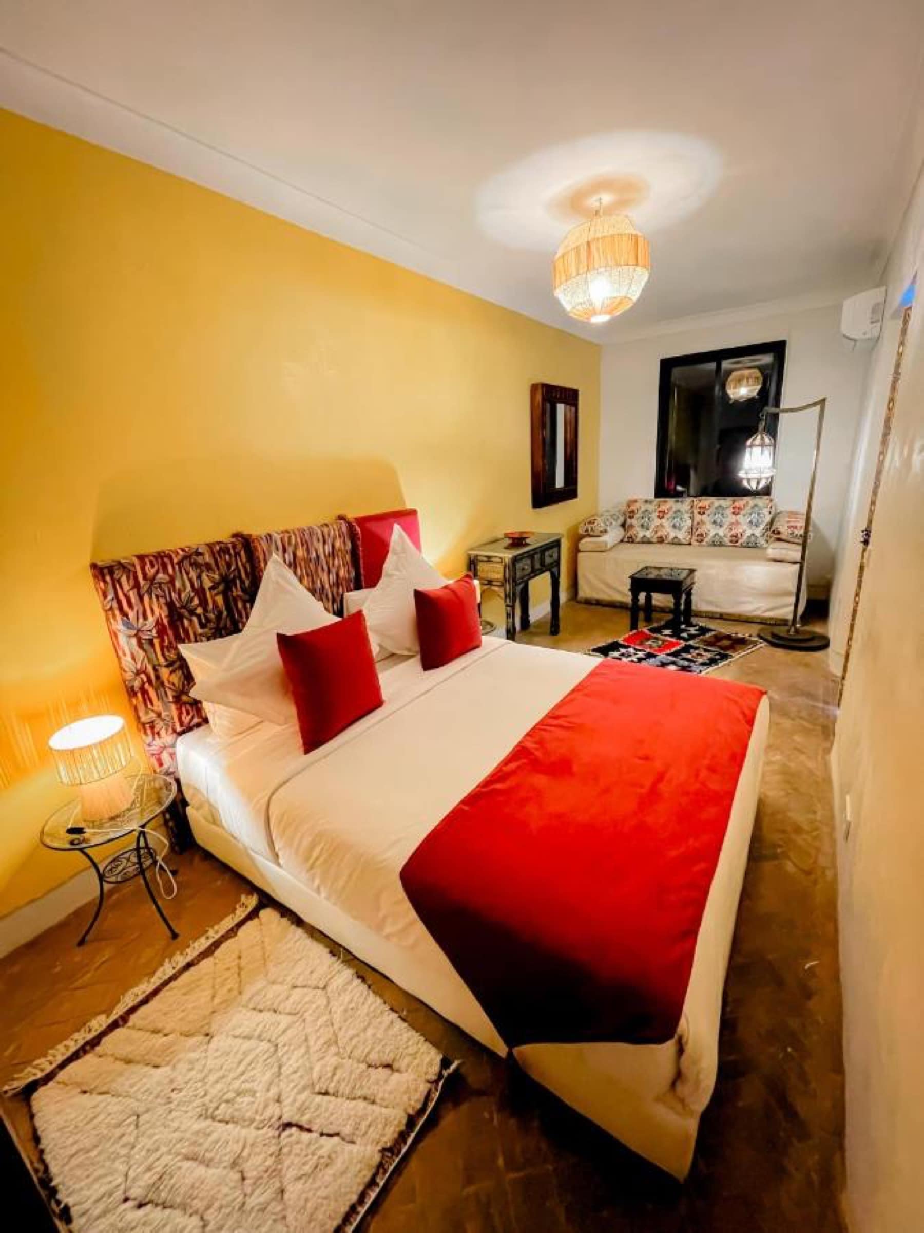 Une chambre jaune, tête de lit fleurie et tapis beni