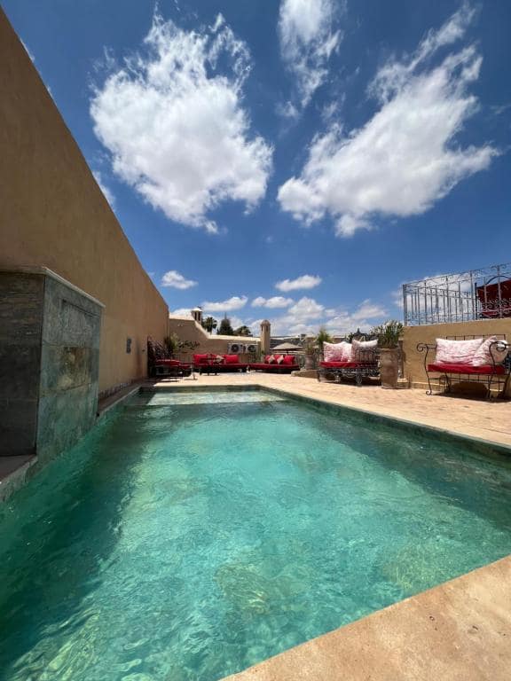 La piscine du toit vue côté salons bas, sous le ciel de la médina