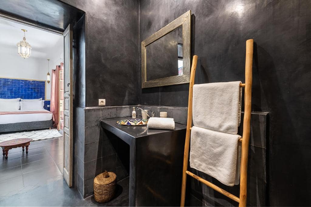 Une salle d'eau en tadelakt noir, sur la chambre à zellige bleu