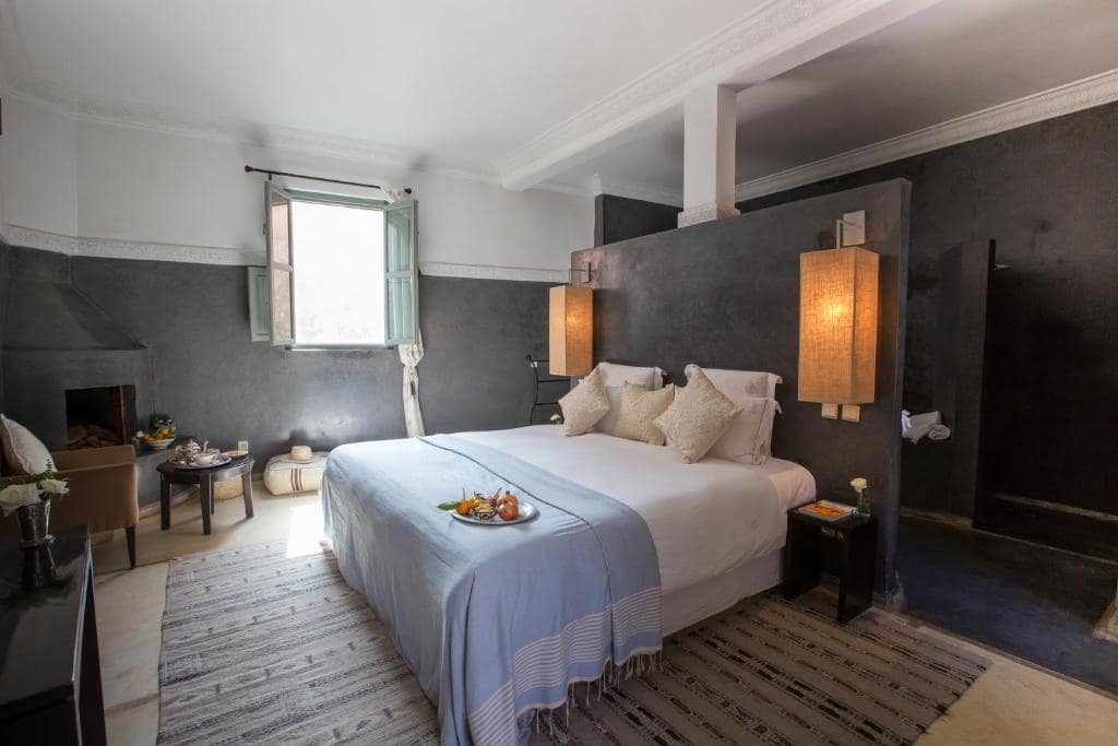 Une chambre en tadelakt gris, cheminée et fenêtre à volets verts