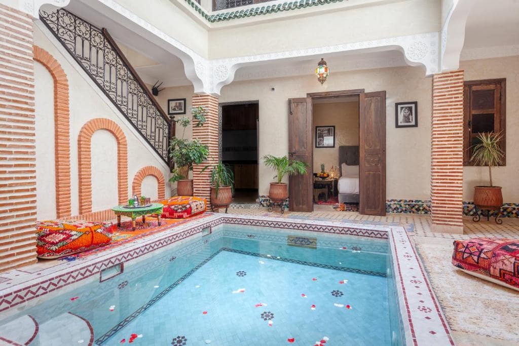 La piscine de la cour, semée de pétales, au pied de l'escalier