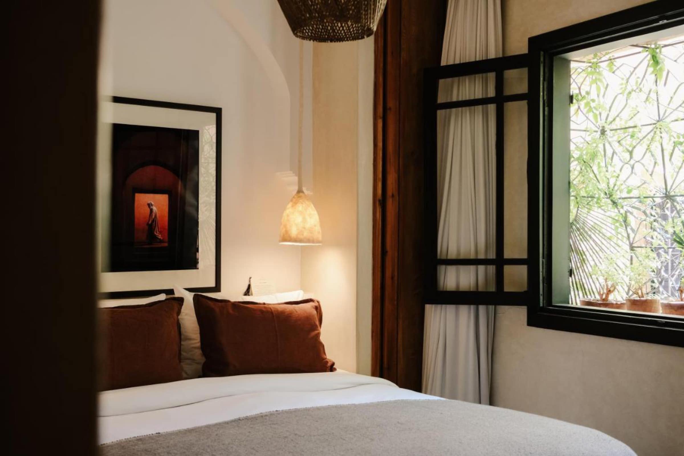 Une chambre en tadelakt, coussins terracotta et fenêtre sur le patio