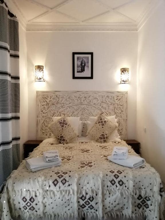 Une chambre, tête de lit en bois sculpté et couvre-lit brodé