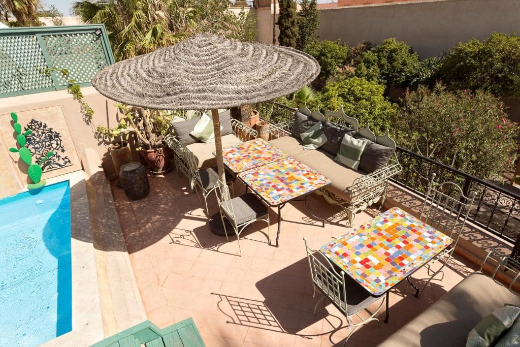 La terrasse du toit, transats au bord du bassin et tables en zellige