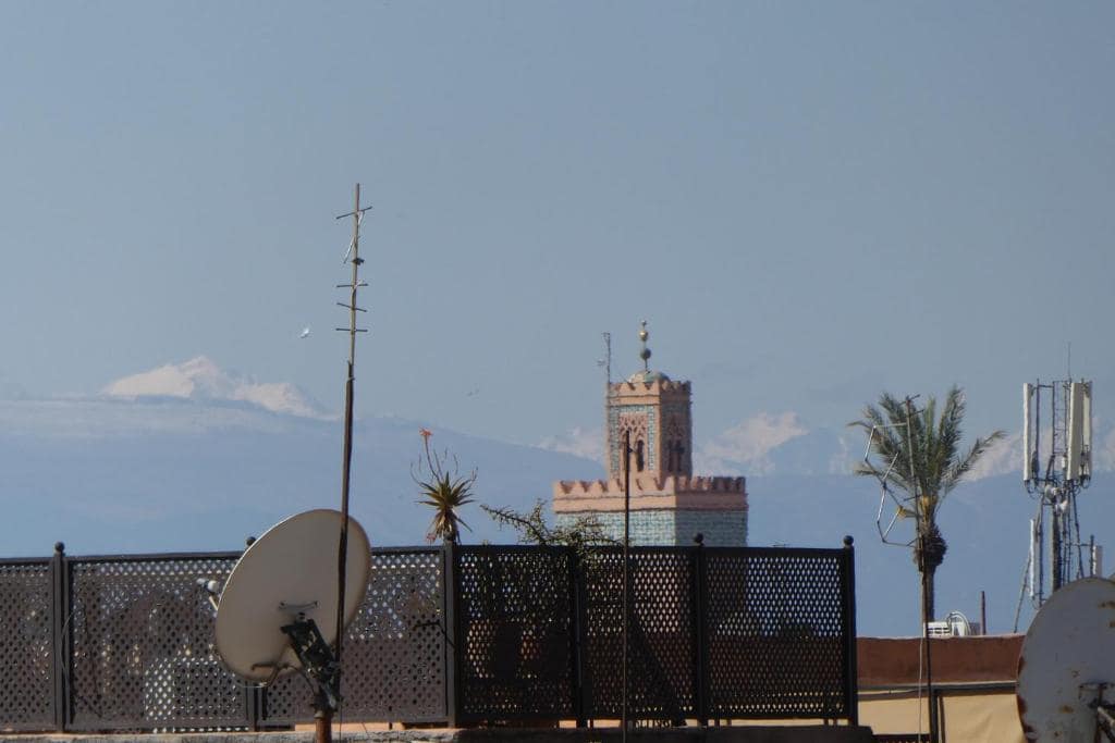 Depuis le toit, un minaret et l'Atlas enneigé au loin
