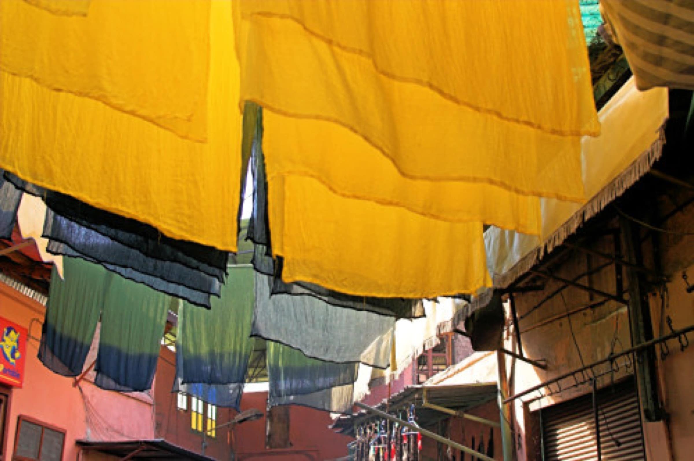 Plafond d'étoffes teintes suspendues au-dessus de la ruelle du souk des teinturiers à Marrakech, jaunes, verts et bleus