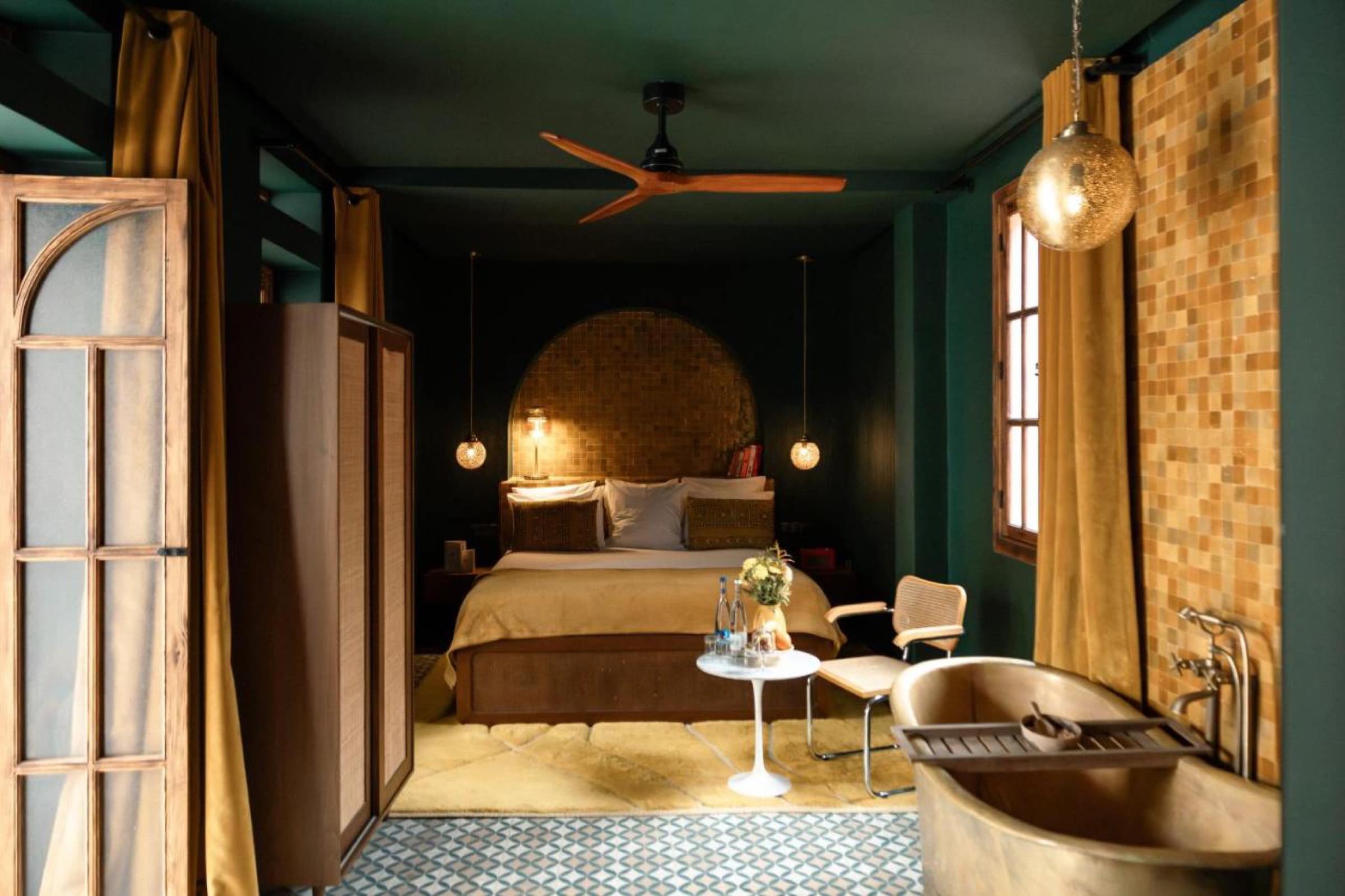 Une chambre vert profond, tête de lit en mosaïque et baignoire en laiton